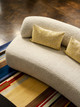 A curved sofa upholstered in Bolton Woven Fabric, adding warmth and texture to a modern, minimalist interior.